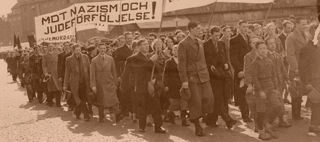Människor går i demonstrationståg. En banderoll med texten "Mot nazism och judeförföljelse.