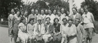 Klassfoto utomhus där kvinnor sitter och står i tre rader och ler mot kameran