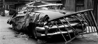 Skadad bil med ett räcke på bilhuvudet.