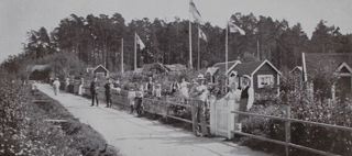 Bilden föreställer människor och hus i ett kokoniträdgårdsområde i Stockholm 1915.