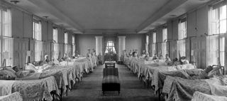 Barn sitter i sängar, läkare och sjuksköterska står bredvid