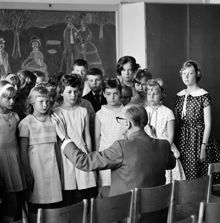 Skolavslutning. Lärare dirigerar klassen. Adolf Fredriks skola. Sjungande barn på skolavslutning i Mariaskola med musiklärare Erik Göransson som körledare.