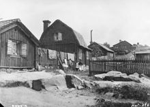 Vy österut. Gränd söder om Bergsprängargränd 6. Några barn står vid staketet där det hänger täcken