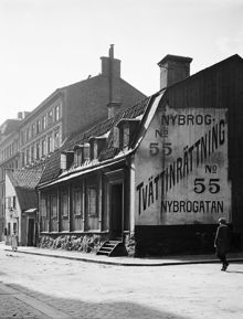 Nybrogatan söderut från Östermalmsgatan. Nybrogatan 55 (nu 75), Hellerströmska tvättinrättningen. En pojke går förbi skylten på gaveln