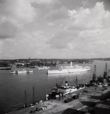 Vy över Saltsjön från Södermalm. Stor passagerarbåt stävar in mot hamnen.