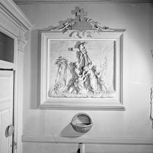 Katolska kyrkan. Ovanför en vigvattenskål sitter en relief föreställande Jesu nedtagning från korset, den så kallade Korsnedtagningen