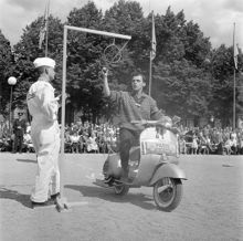 Vespa-tävling i Kungsträdgården. I tävlingen gällde det att bl a flytta ett glasvatten. En fransman rev allt som gick att riva och folket jublade då han lyckades få allt vattnet i glaset i ansiktet