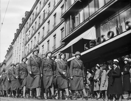 Luftskyddsparad med kvinnor i uniform och hjälmar som marscherar på Sturegatan.