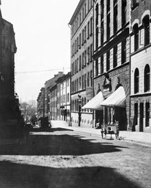 Styrmansgatan söderut från Storgatan. T.h. vid dragkärran ligger Styrmansgatan 23 med en matvaruhandel. I fonden, vid Strandvägen, skymtar ett segelfartyg