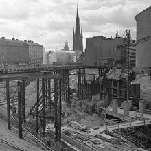 Kvarteren Faunen, Stigbygeln och del av Sporren är rivna. Mäster Samuelsgatan går på en bro över tunnelbanebygget. T.v. Klarabergsgatan 23-25, kv. Skansen. Bild mot sydväst med Klara kyrka i fonden