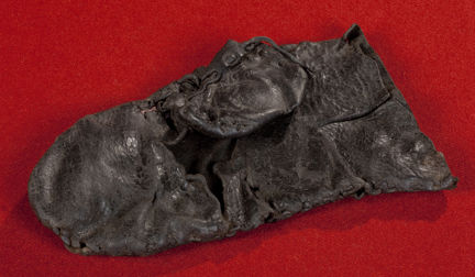 Medeltida tumhandske av läder. Fotograferat mot röd bakgrund.