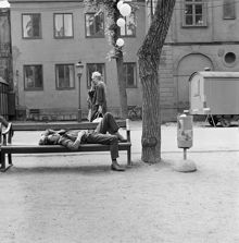 Liggande man på parkbänk i Kungsträdgården