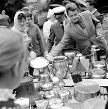 Auktion. Besökare kring ett bord med auktionsgods