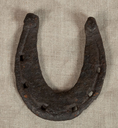 Medeltida hästsko av järn. Fotograferad mot gråbrun bakgrund. 