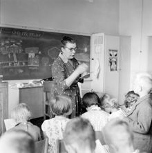 Skolavslutning. Lärarinna delar ut betyg i klassrummet. Enskedefältets skola