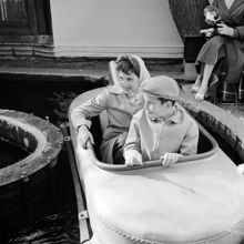 Mats Lindgren och Ingvor Lindgren åker på vattenbana på Gröna Lund. Kvinnlig fotograf håller kamera och blixt i bakgrunden