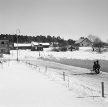 Vy från sydväst mot Anneboda gård längs Sylvestergatan med kälkåkande barn. Till vänster skymtar radhuset vid Sylvestergatan 12.
