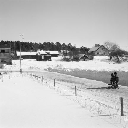 Vy från sydväst mot Anneboda gård längs Sylvestergatan med kälkåkande barn. Till vänster skymtar radhuset vid Sylvestergatan 12.