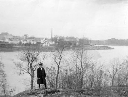 En yngling står i Södra Hammarbyhamnen med Hammarby Sjö och Barnängens fabriker i fonden.
