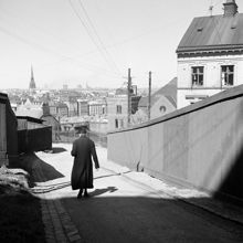 En kvinna går Höga Stigen norrut mot Glasbruksgatan. Utsikt mot Gamla Stan i fonden