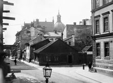 Artillerigatan söderut från Linnégatan. Trähuset som låg vid Artillerigatan 17 och Linnégatan 42 revs 1904. Nuvarande Artillerigatan 35. I fonden ses Hedvig Eleonora kyrkas torn