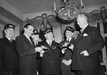 Österlånggatan 51, Gyldene Freden. Sällskapet Stadsbudskåren. Ordförande Erik Bullen Berglund överlämnar mössor till två av de nya stadsbuden, Lorens Marmstedt och Carl Albert Anderson