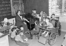 Interiör från klassrum i Eugeniahemmet med skolklass och fröken Lundström.