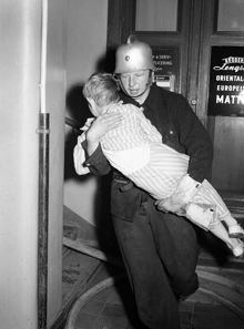 Mäster Samuelsgatan 46. Brandman bär ut 7-åriga Karl Gustav Harald. Eldsvåda uppstod i huset efter att en brottsling, en dynamitard, försökt spränga ett kassaskåp i ett försäljningskontor.