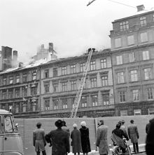 Grupp av åskådare betraktar släckningsarbete på taket till Arvid Nordquist HAB, Biblioteksgatan 27