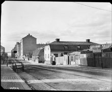 Roslagsgatan norrut mot korsningen med Surbrunnsgatan. Närmast t.h. kv. Målaren. På andra sidan Surbrunnsgatan ligger kv. Väduren med det gamla värdshuset Clas på Hörnet