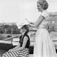 Två kvinnor svalkar sig på en takterrass i värmen