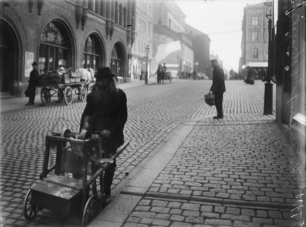 En skärslipare med sin vagn och slipsten på Nybrogatan utanför Östermalms Saluhall.