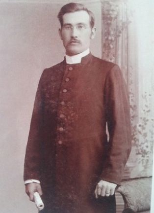Ateljéporträtt av en man med prästkrage, glasögon och mustasch