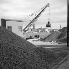Söder Mälarstrand. Grushögar och en lyftkran på kajen. Riddarholmen i fonden