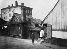 En kvinna och en pojke står på gårdssidan av Bengt Ekehjelmsgatan 16. Bostadshuset i norr ligger vid Högbergsgatan 70. Den här delen av Bengt Ekehjelmsgatan är nu igenlagd och ingår i kv. Hållkarlen