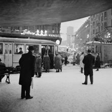 Stureplan under Svampen, vy mot Kungsgatan. Folk kliver på spårvagn på Birger Jarlsgatan i snöyran
