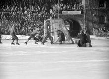 Stadion. SM-finalen i Bandy mellan Nässjö och Edsbyn. Högerytter Uno Wennerholm (nr 7) skjuter direkt på tennisslag och bollen tar just ovanför hatten på den hukande måldomaren