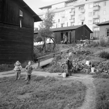 Kv. Ruddammen mellan Körsbärsvägen och Valhallavägen. Dam pumpar vatten vid nödbostäderna, barn leker på gården