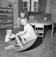 Stora Nygatan 40-42, Yrkesskolan. Barn gungar gungbräda inomhus (medan deras mödrar provar kläder eller går på kurs i husbehovssömnad)