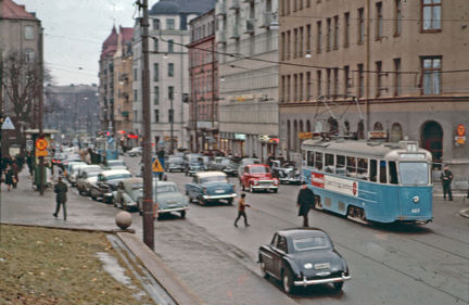 Bilar, en spårvagn och gångtrafikanter.