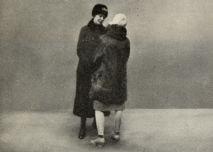 Svartvitt foto där en kvinnlig frälsningssoldat, med ansiktet vänt mot oss, talar med en kvinna som har ryggen mot oss.