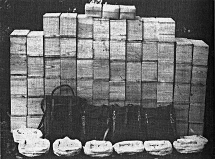 Kornig, svartvitt foto på vita lådor eller paket i travar, och ryggsäckar