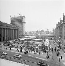 Hötorget med provisoriska Hötorgshallen söderut. Första höghuset är under byggnation. Nya Elementarskolan i fonden