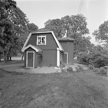 Svartvitt foto på rödmålat(?) torp med vita knutar.