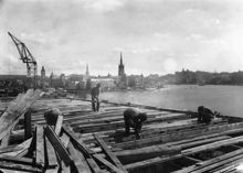 Timmermän i arbete med bjälklagen på södra längan. Utsikt över Riddarholmen och Södermalm.