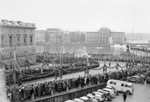 Slottsbacken med utsikt mot Norrström. Gustaf V:s begravningsprocession. Åskådare kantar gatan. I förgrunden t.h. buss med SF-logotyp