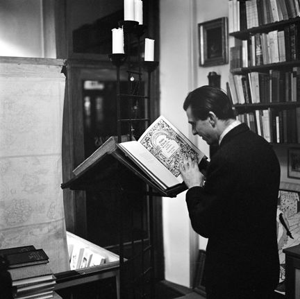 Antikvariatsinteriör, en man bläddrar i en stor bibel på ställning.