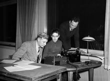 Holländargatan 32. Internationell studentkonferens i Stockholms Högskolas kårhus. Två unga män och en kvinna vid en skrivmaskin och en bandspelare