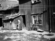 Gårdssidan vid Styrmansgatan 20 (nuvarande 16). En kvinna står bredvid en balja med tvätt och ett träkar