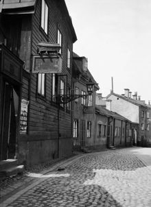 Stora Glasbruksgatan västerut vid Stora Glasbruksgatan 42. Ovanpå skylten står en likkista